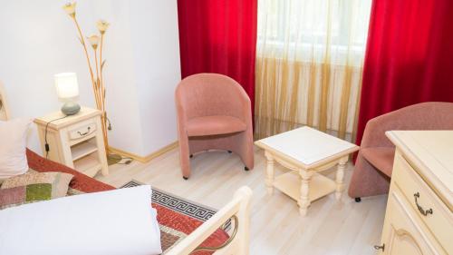 a living room with red curtains and chairs and a table at Hotel TEX Club in Botoşani