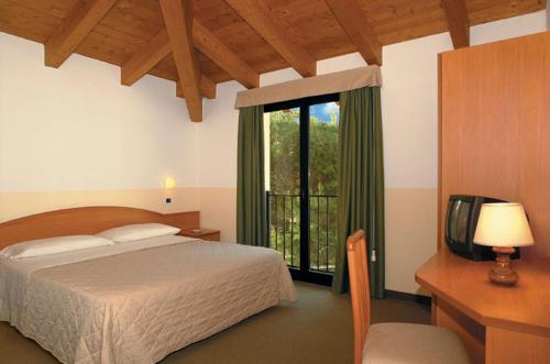 a bedroom with a bed and a tv and a window at Albergo Ristorante Alla Lanterna in Fano