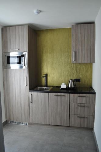a kitchen with wooden cabinets and a sink and a microwave at Van der Valk Hotel Nuland - 's-Hertogenbosch in Nuland