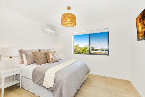 a white bedroom with a bed and a window at Dreamtime Villas by Kingscliff Accommodation in Kingscliff
