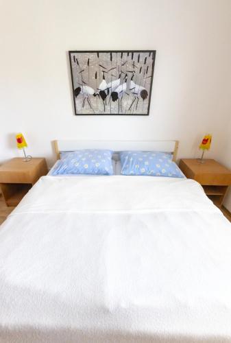 a bedroom with a white bed with two tables at Apartman Hugo in Veľký Slavkov