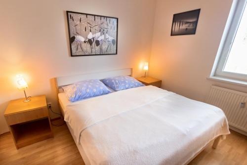 - une chambre avec un lit blanc et deux lampes dans l'établissement Apartman Hugo, à Veľký Slavkov
