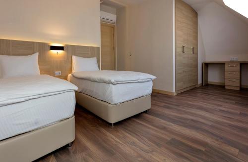 two beds in a small room with wooden floors at Princess Residence in Istanbul