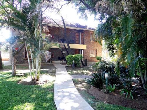 a house with palm trees in front of a building at Lepha Guest House in Onverwacht