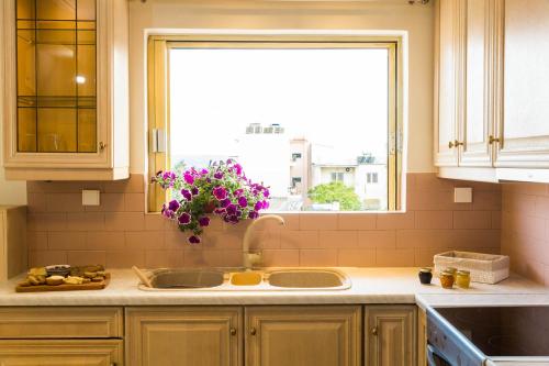 una cocina con fregadero y una ventana con flores púrpuras en For4 Seasons Home 1 - by Avelink, en Spáta