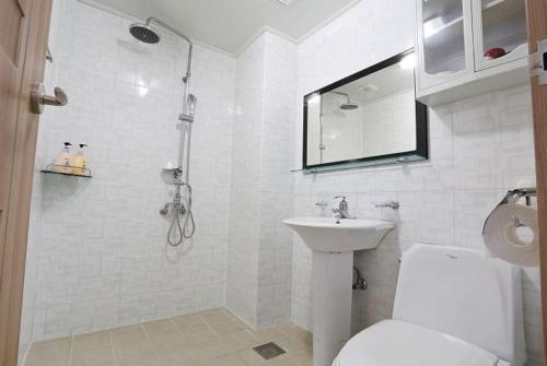 a bathroom with a shower and a toilet and a sink at HY Choi Hostel in Seogwipo