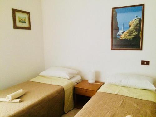 a room with two beds and a picture on the wall at A Due Passi in La Maddalena