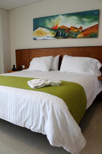 a large bed with a green and white blanket at Hotel Atrium Plaza in Barranquilla