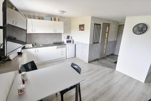 a kitchen with white cabinets and a table and chairs at Apartmán Theo in Veľký Slavkov