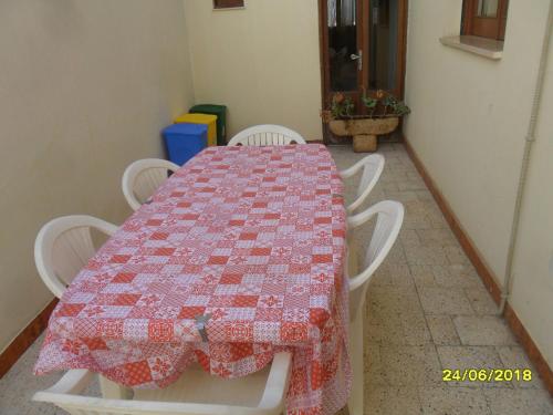 a table with white chairs and a quilt on it at Casa Elisa in Ruffano