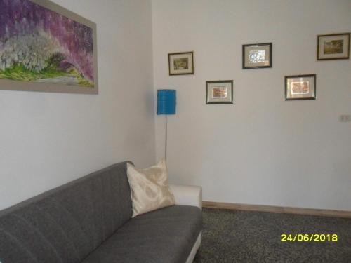 a living room with a gray couch and pictures on the wall at Casa Elisa in Ruffano