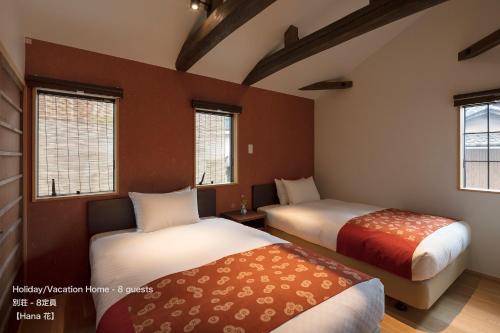 京都市にあるTHE MACHIYA VILLA 三条しらかわ小路のベッド2台と窓2つが備わる客室です。