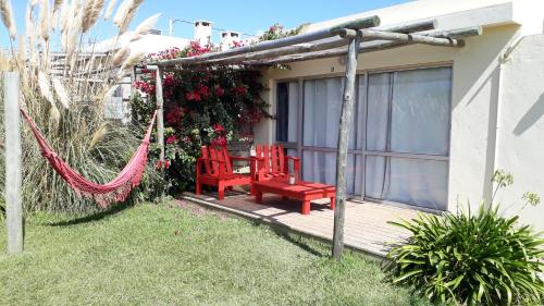 two red chairs on a porch with a swing at Dejeps in Punta Del Diablo