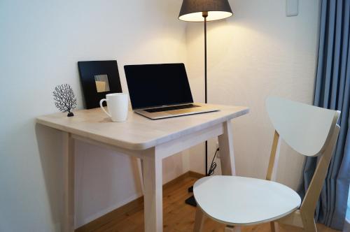 a laptop computer sitting on a white desk with a chair at Hotel Miyakojima in Miyako Island