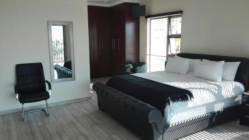a bedroom with a large bed and a chair at Estoby Executive guest house in Witbank