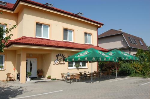 two green umbrellas and tables and chairs in front of a building at Penzion Jarka in Bratislava