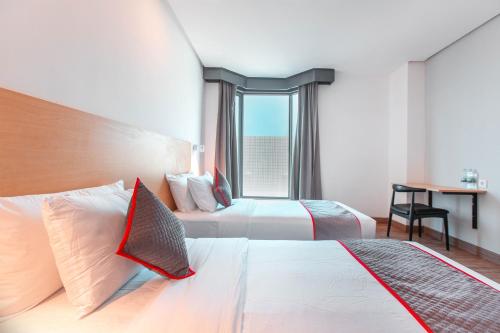 a hotel room with two beds and a window at SUPER OYO Townhouse 1 Hotel Salemba in Jakarta