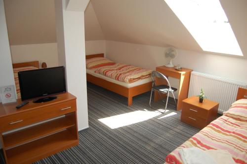 sypialnia z łóżkiem, telewizorem i biurkiem w obiekcie Penzion Jarka w Bratysławie