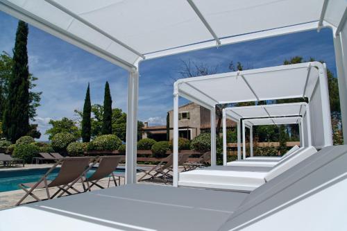 a white pergola next to a swimming pool at Hôtel du Château & Spa - Teritoria in Carcassonne