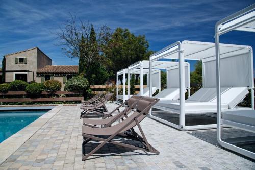 a group of lounge chairs next to a pool at Hôtel du Château & Spa - Teritoria in Carcassonne