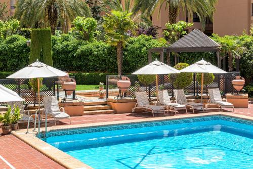 a swimming pool with lounge chairs and umbrellas next to at Hotel Saray in Granada