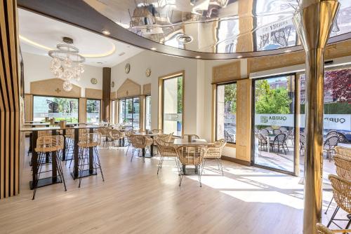 une salle à manger avec des chaises, des tables et des fenêtres dans l'établissement Hotel Saray, à Grenade