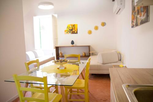 a dining room and living room with a glass table and yellow chairs at Villa Mallandrino in Mondello