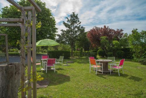 a group of chairs and tables with an umbrella at Les Chambres du Vivier, chambres d'hôtes et gîte - à 100m - in Durbuy