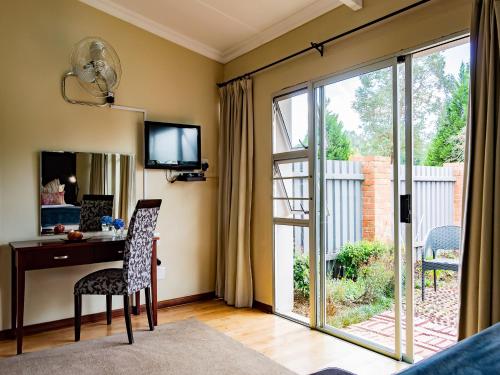 a living room with a desk and a sliding glass door at Brahman Hills - Gardens, Hotel & Cottages in Nottingham Road