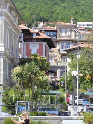 a woman sitting on a bench in a city at Stefani Studio Apartman in Opatija