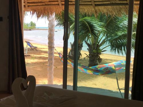 a view of a beach with a hammock and a palm tree at Sunrise Beach Resort in Ko Chang