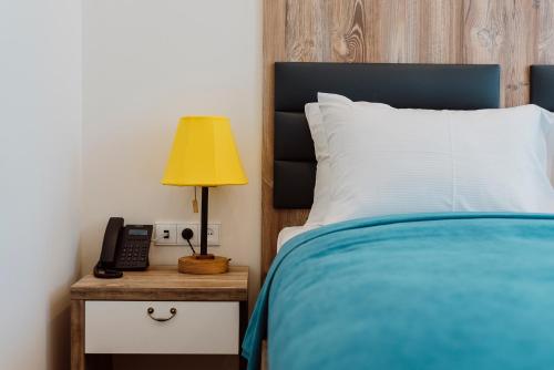 a bed with a lamp and a phone on a night stand at Boulevard Hotel Batumi in Batumi