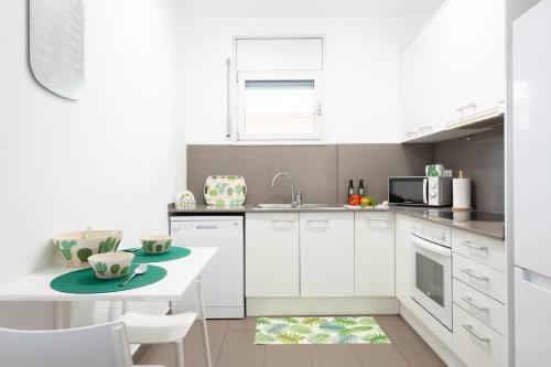 a kitchen with white cabinets and a table and a microwave at Apartamentos Cornellalux in Cornellà de Llobregat