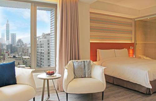 a bedroom with a bed and two chairs and a window at Park Taipei Hotel in Taipei