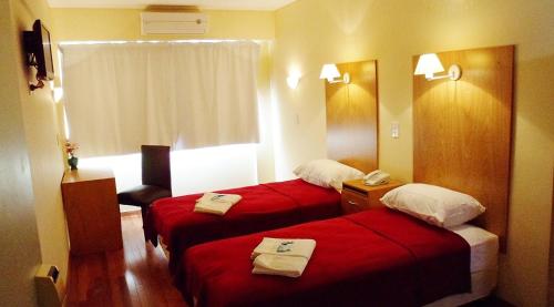 two beds in a hotel room with red sheets at Hotel Juramento in Buenos Aires