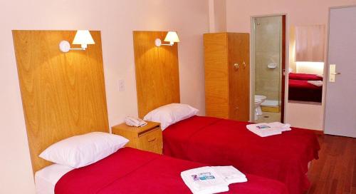two beds in a hotel room with red sheets at Hotel Juramento in Buenos Aires