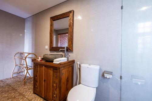 a bathroom with a toilet and a mirror at D'jineng Rice Terrace Canggu in Canggu