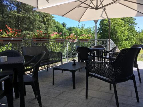 a patio with tables and chairs and an umbrella at Hotel Langhe & Monferrato in Costigliole dʼAsti