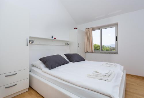 a white bedroom with a white bed and a window at Molnar Resort Apartment Ljiljana in Brzac