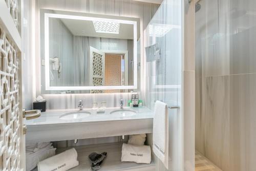 Baño blanco con lavabo y espejo en Hotel Saray, en Granada