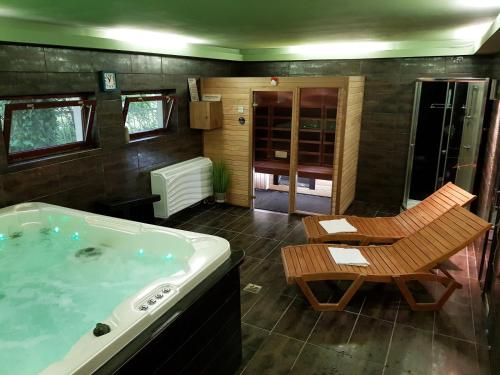 a bathroom with a tub and a table and a chair at Erdővarázs Panzió in Lillafüred