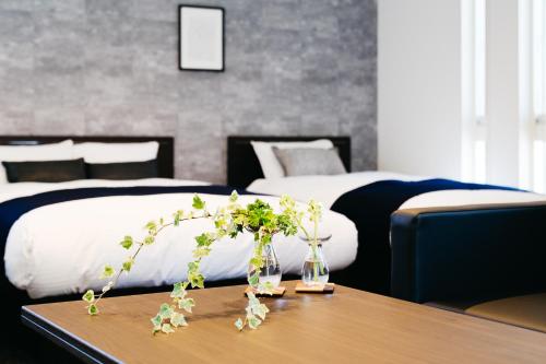 a hotel room with two beds and a table with flowers at FUKUOKA MOJIKO STAY in Kitakyushu