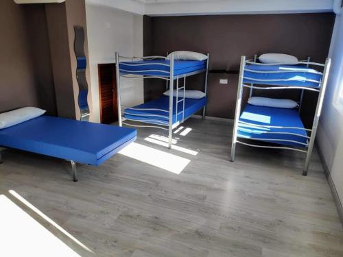 a room with three bunk beds and a table at Albergue Mar de Rostro in Finisterre