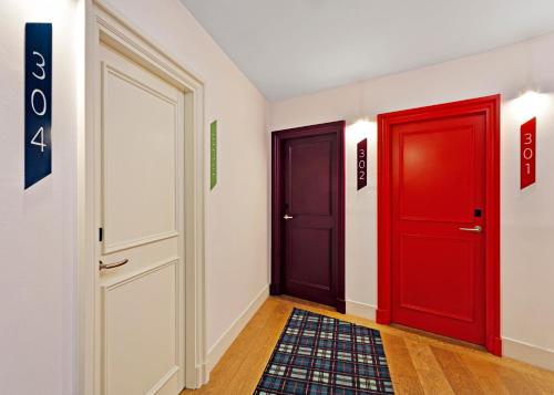 a hallway with two red doors and a rug at One Shot Prado in Madrid