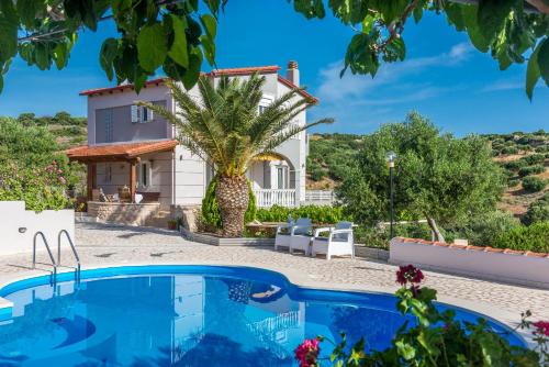 a villa with a palm tree in front of a house at Villa Palma in Sitia