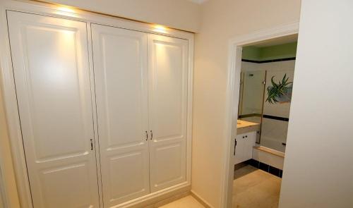 baño con armarios blancos y espejo en Mogán suite, en Puerto de Mogán