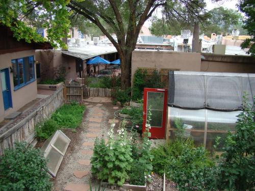 a garden with a red door and some plants at The Historic Taos Inn in Taos