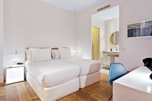 a white bedroom with a bed and a blue chair at One Shot Prado in Madrid