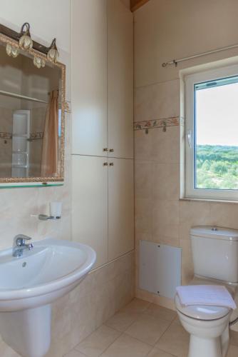 a bathroom with a sink and a toilet and a window at Villa Palma in Sitia