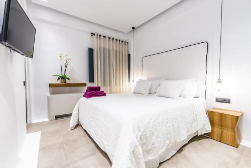 a bedroom with a white bed and a flat screen tv at Portes Suites & Villas Mykonos in Mýkonos City